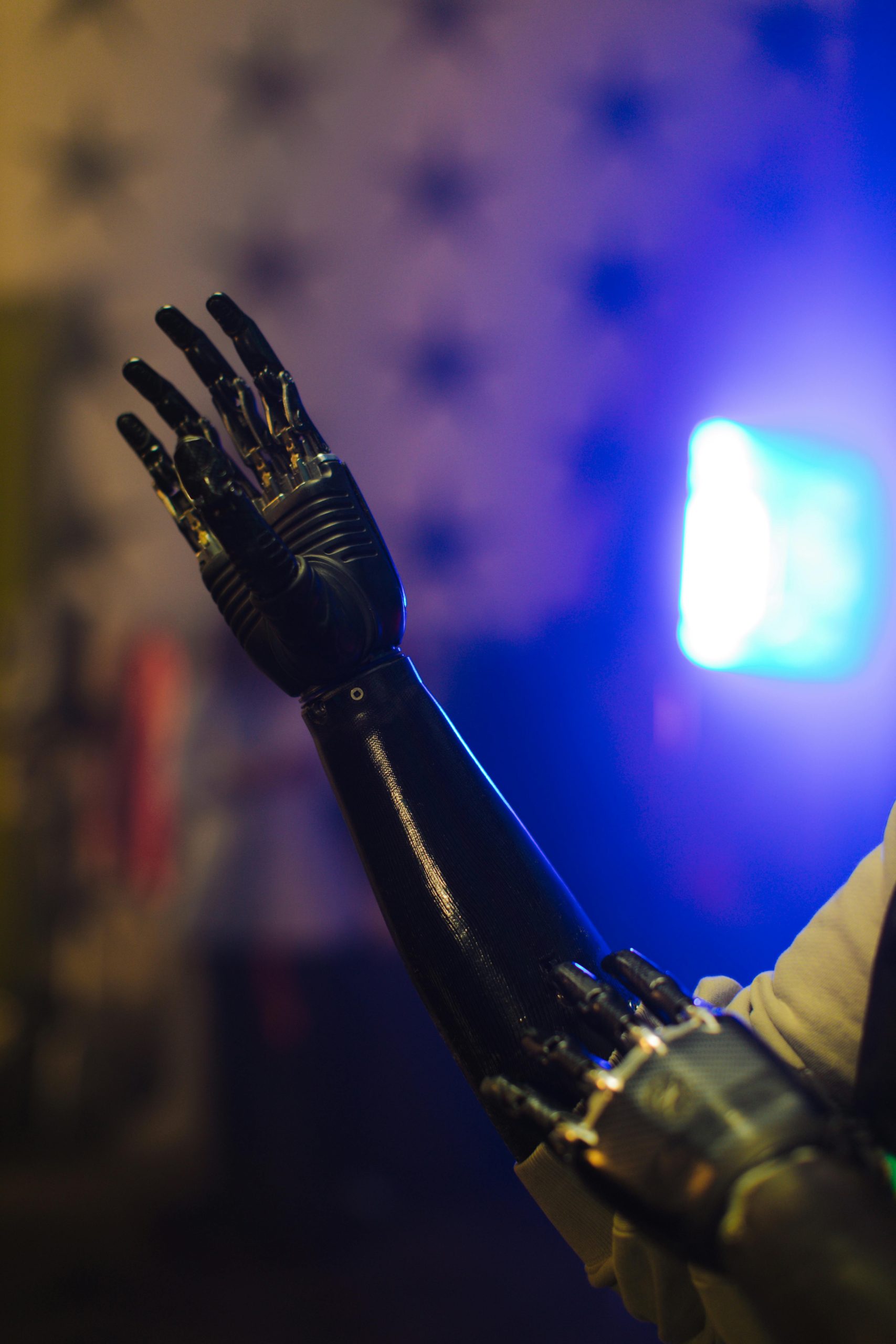 Close-up of a robotic arm with illuminated blue background, showcasing advanced technology.